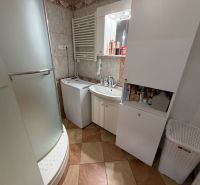 Bathroom in a 3-room apartment with a washing machine, shower cabin, and storage cabinets.