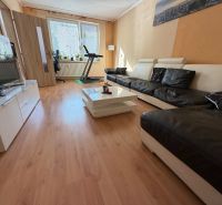 Living room with a leather sofa and a wooden decor floor in a 3-room apartment.