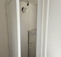 A narrow space with white doors and simple lighting in a family house.
