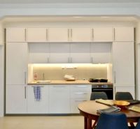 A kitchen in a 3-room apartment with a white kitchen unit and a dining table.