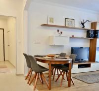 Dining area with four chairs and a TV in a 3-room apartment.