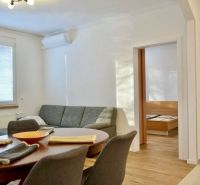 Living room in a 3-room apartment with a sofa, dining table, and wooden decor flooring.