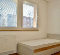 Bedroom in a 3-room apartment with large windows and a wooden decor floor.