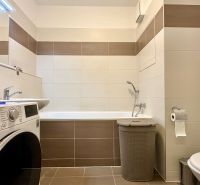 A bathroom in a 3-room apartment with a bathtub, washing machine, and toilet.