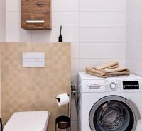 Bathroom in a 2-room apartment with a washing machine, toilet, and storage cabinet.