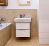 A bathroom with a shower tub, sink, and tiles in a 2-room apartment.