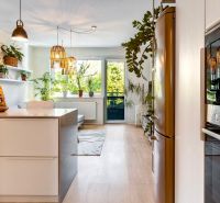 A kitchen in a 2-room apartment with a wood-patterned floor and lots of plants.
