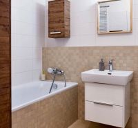 A bathroom in a 2-room apartment with a bathtub, white sink, and wooden decor.