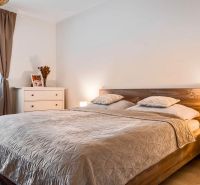 Bedroom in a two-room apartment with a bed, night lamps, and a floor with a wooden decor.