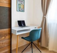 A workspace in a 2-room apartment with a blue chair and a white desk.