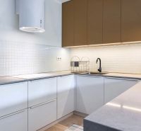 A kitchen in a two-room apartment with white cabinets, a black faucet, and appliances.