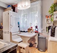 A kitchen in a 2-room apartment with a dining area and appliances, wooden decor flooring.