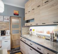 A kitchen in a 2-room apartment with a wooden decor floor and light furniture.