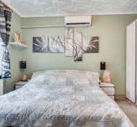 A bedroom in a 2-room apartment with air conditioning and abstract paintings on the wall.