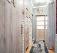 A narrow hallway of a 2-room apartment with wooden decor and furnishings.