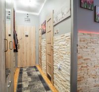A hallway in a 2-room apartment with stone on the walls and decorative lighting.