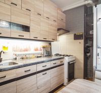 A kitchen in a 2-room apartment with a wooden decor floor and appliances.