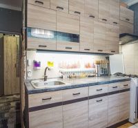 A kitchen in a 2-room apartment with a wooden decor floor and a practical kitchen unit.