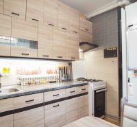 A kitchen in a 2-room apartment with wooden decorative cabinets and a gas stove.