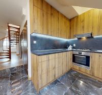 A kitchen in a 4-room apartment with a wooden decor floor and a spiral staircase.
