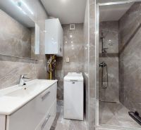 A bathroom with a shower and a washing machine in a 4-room apartment.