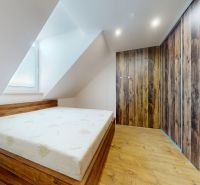 Bedroom with a slanted ceiling, built-in wardrobe, and wooden decor flooring in a 4-room apartment.