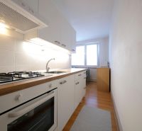 A kitchen in a 2-room apartment with white cabinets and a wood-patterned floor.