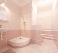 A bathroom with tiles and a shower in a 2-room apartment with soft shades of beige.