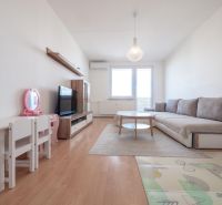Living room in a two-room apartment with a wooden decor floor, a children's table, and a sofa.