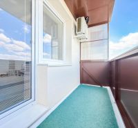 A balcony of a 2-room apartment in Nitra with a view of the sky and air conditioning.