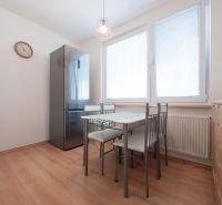 A kitchen with a wooden decor floor, dining area, and appliances in a two-room apartment.