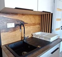 A sink in a holiday apartment with a wooden decor floor and a countertop.