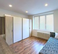 A room with a bed, a wardrobe, and a floor with a wooden decor in a holiday apartment.