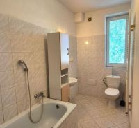 Bathroom with a bathtub and a window in a studio apartment, tiles and ceramics.