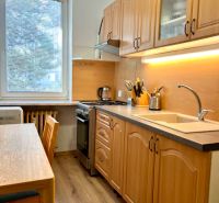 A kitchen in a 2-room apartment with wooden furniture and a floor with a wooden decor.