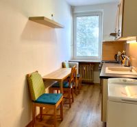 A kitchen with two chairs and a wooden-patterned floor in a two-room apartment.