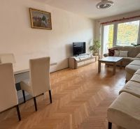 Living room in a 4-room apartment with a large sofa, dining table, and wooden decor flooring.