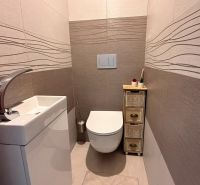A cozy toilet with a simple sink and decorative tiles in a 4-room apartment.