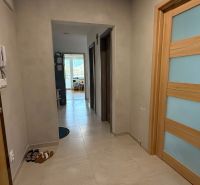 A hallway with light tiles and wooden doors in a 4-room apartment.