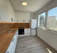 A kitchen in a 3-room apartment with white cabinets and a wood-patterned floor.