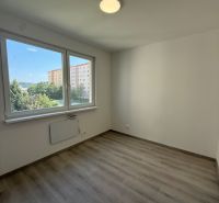 A room in a three-room apartment with a wooden decor floor and large windows.
