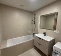 Bathroom in a 3-room apartment with a bathtub, sink, and washing machine, beige tiles.