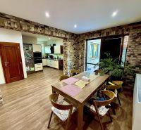 Dining room in a family house with brick cladding and a wooden decor floor.