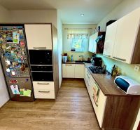A kitchen in a family house with a wooden decor floor, a fridge with magnets.