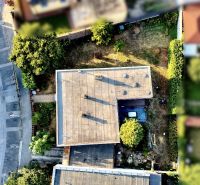 Aerial view of the roof of a family house in Nové Zámky surrounded by greenery and a road.