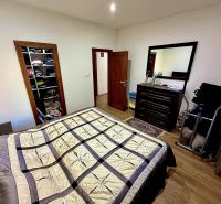 A bedroom in a family house with a wooden decor floor, a bed, and a wardrobe.