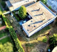 A family house in Nové Zámky with a flat roof and a landscaped garden full of greenery.