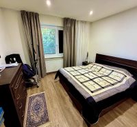 Bedroom with wood-patterned flooring in a family house, bed, curtains, mirror.