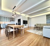 Living room in a 3-room apartment with a kitchen, dining table, and wooden decor flooring.