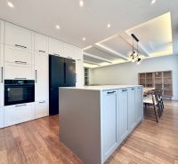 A kitchen with an island in a 3-room apartment, a floor with a wooden decor, dining room.